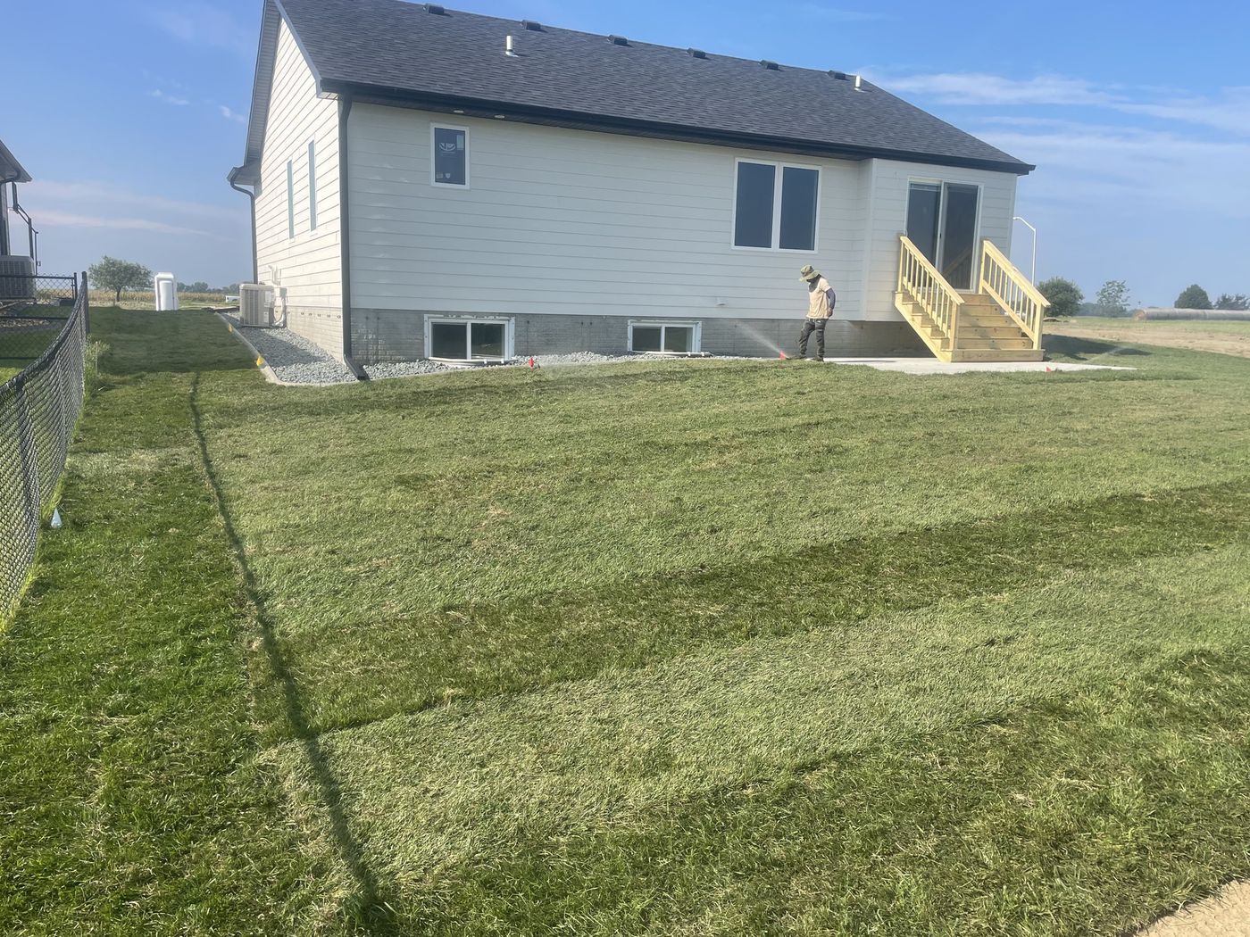 Residential backyard sod installation, after — full green lawn behind the same home and fence line
