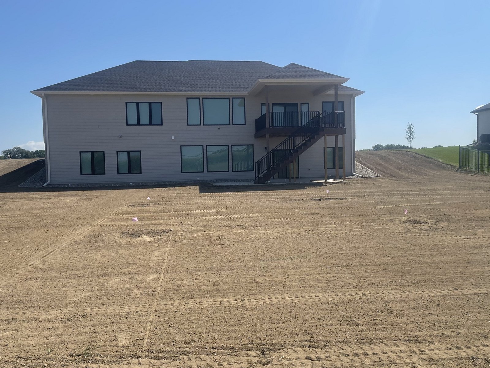White two-story home on a bare graded slope before sod installation